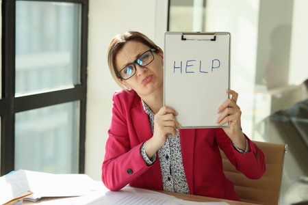 Worried woman in the office holding an inscription helpの写真素材