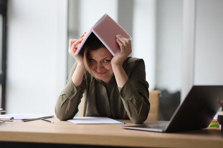 The woman in the office hid under a notebook on her head