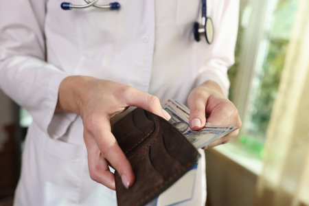 Female doctor hides money in wallet in hospital.の写真素材