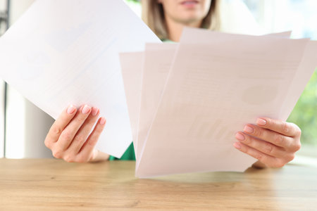 Business woman reviews many documents while sitting at office.
