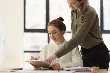 Boss woman pointing at documents while standing near her young manager.の写真素材