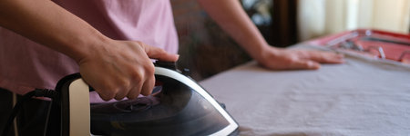 Housewife irons bed linen on ironing boardの写真素材