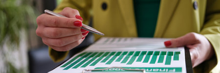 Business woman holds pen and points to clipboard to check business informationの写真素材