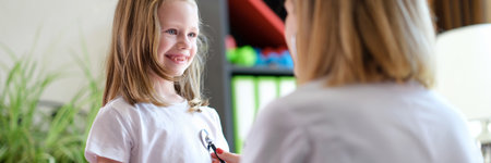 Pediatrician listens to lungs of little girl child with stethoscopeの写真素材
