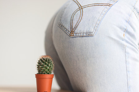Woman in jeans sits on spiked cactus growing in brown potの写真素材