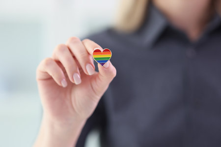 Woman holding small heart with LGBT flag colors closeupの写真素材