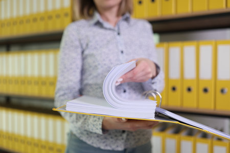 Female employee looks for accounting papers in ring binderの写真素材