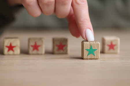 Finger of woman touches kids wooden cube with green starの写真素材