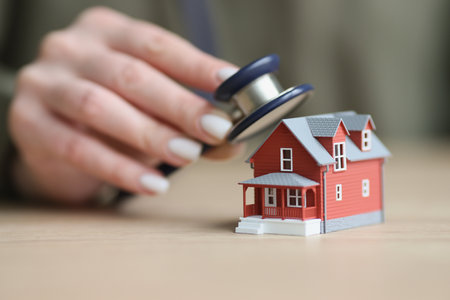 Hand of woman puts stethoscope to house to check conditionの写真素材