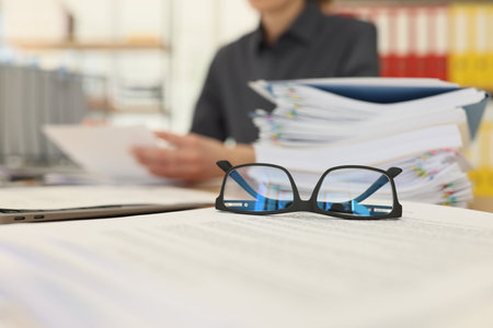 Glasses put on papers near stack of folders with documents