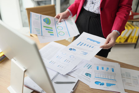 Woman sorts document papers with statistics and diagramsの写真素材