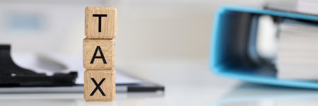 Tax text on wooden cubes on table with documentsの写真素材