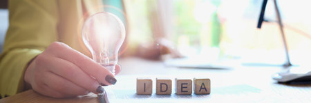 Businesswoman holds light bulb and on cubes word ideas closeupの写真素材