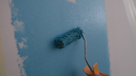 Closeup of person with bright blue paint blue paint on white wallの写真素材
