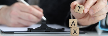 Hand holds wooden cube block with text TAXの写真素材
