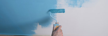 Man paints white wall with blue dye closeupの写真素材