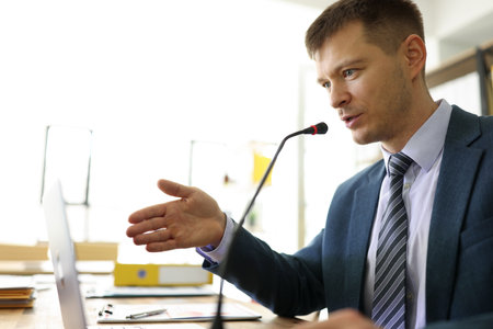 Focused manager speaks in microphone at online seminarの写真素材