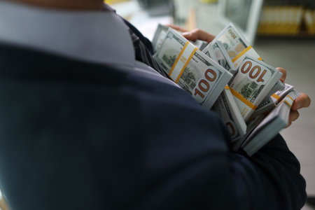 Successful manager holds counted stacks of money in hands