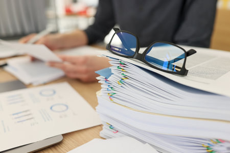 Glasses for eyesight lie on stack of documents at workplace
