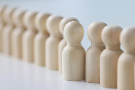 Small wooden figurines put in long row on white tableの写真素材
