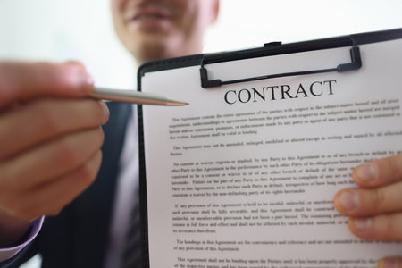 Businessman holds clipboard in hand pointing pen to contractの写真素材