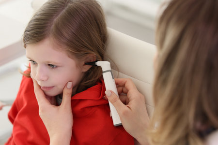 Caring therapist checks ears of little girl with otoscopeの写真素材