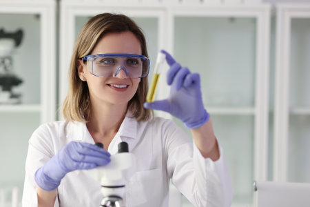 Laboratory assistant examines sample of liquid in test tubeの写真素材