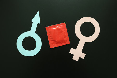 Male and Female symbols with condom on black backgroundの写真素材