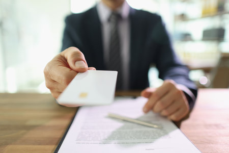Man in suit holds credit card ready to pay for servicesの写真素材
