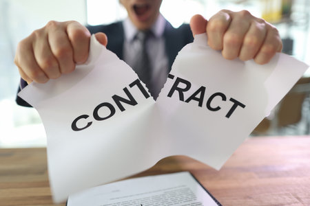 Irritated man tears contract paper apart sitting at tableの写真素材