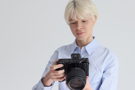 Short haired blonde woman adjusts digital photo camera