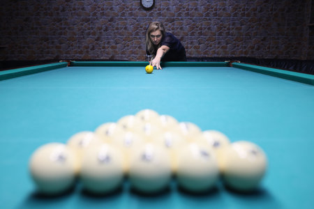 Concentrated player directs ball to pyramid on pool tableの写真素材