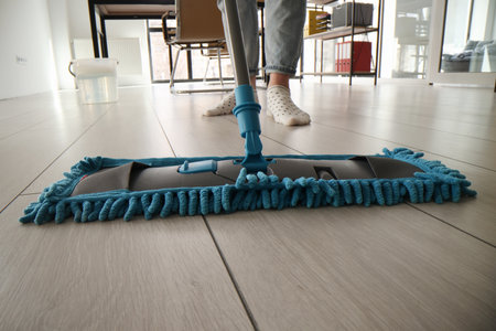 Housewife cleans floor with wet fluffy mop in living room