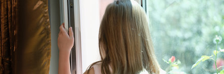 Girl in pink dress standing on windowsill at open windowの写真素材