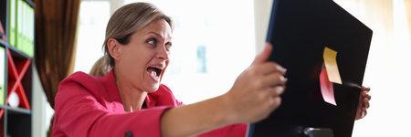 Businesswoman screaming hysterically at computer monitor in officeの写真素材
