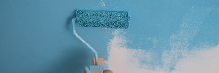 House painter paints wall blue with roller closeupの写真素材