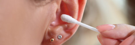 Woman cleaning ears and using cotton bud