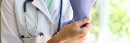 Doctor practitioner in medical gown and wearing gloves posing in clinic officeの写真素材