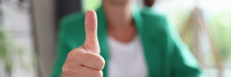 Businesswoman sitting at workplace and showing thumb up signの写真素材