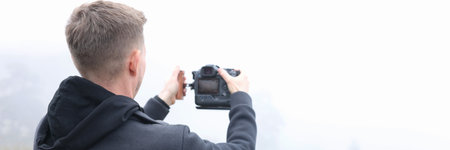 Young male photographer in foggy meadow taking pictures.の写真素材