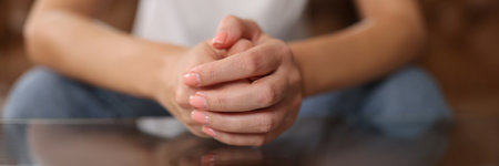 Close up of connected hands of woman sitting at table.