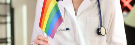 Woman doctor shows lgbt pride flag in her hand in hospital office.の写真素材