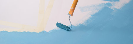 Paint roller paints white wall with blue color, copy space for text.の写真素材