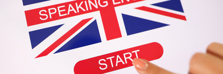Tablet with British flag and words speaking English, womans finger touches start button.