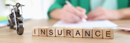 Motorcycle model and words insurance from wooden cubes on table, manager with document in backgroundの写真素材