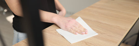 The female hand wipes wooden shelf with napkin, close-upの写真素材