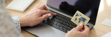 A woman dials credit card number on a laptop keyboard
