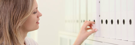 Female doctor pick up one folder from row in medical clinic.の写真素材