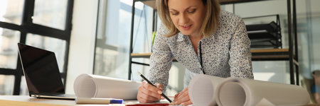 Woman architect draws her project on whatman paper in office.