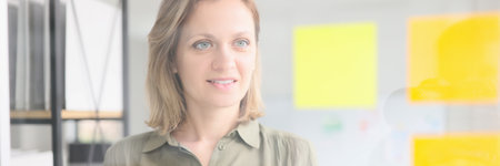 Female employee puts yellow sticky notes on glass in office